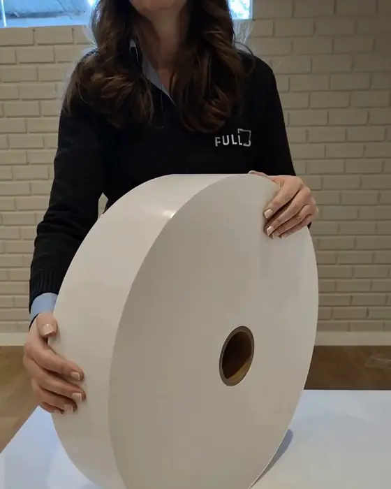 Funcionária da Full de uniforme com o logo bordado, segurando uma bobina no estoque