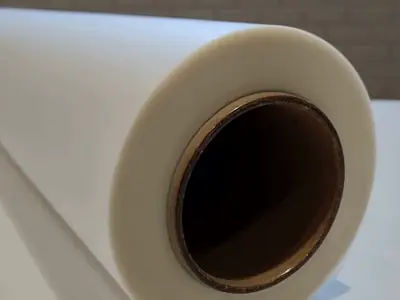 Ponta de uma bobina de filme DTF têxtil com o tubete, sobre a mesa